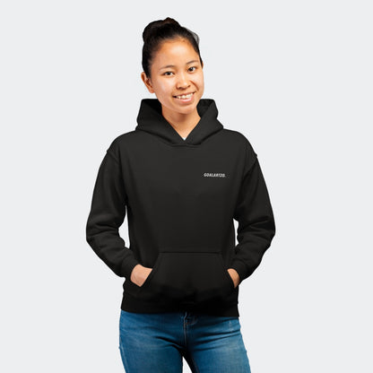 Female asian model smiling facing the camera standing in a photo studio. She is wearing a black hoodie which has a small white logo reading 'goalartzo' on the left chest.